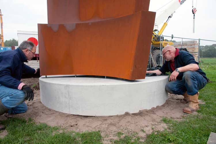 Het beeld laten wij zakken in de vóórgeboorde gaten op de zelfverhardde betonnen sokkel.